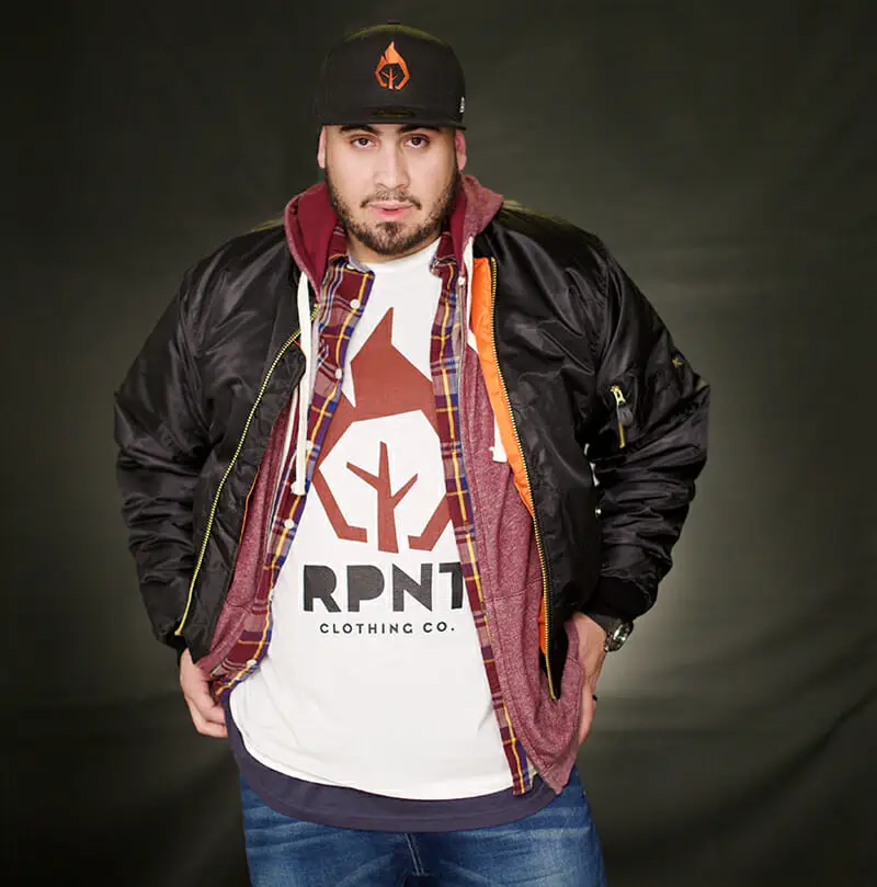 Man in black jacket and red hat posing against black background.