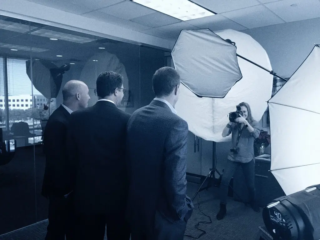 Photographer with Camera Taking a Portrait Shot of Men in Suits in a Photo Studio with Large Softbox Lights and Equipment Nearby
