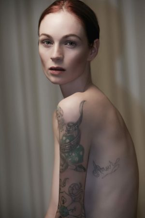 Amour Red headed model posing nude with tattoos in McKinney TX.