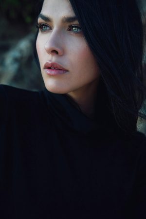Black and Blue Model with dark hair and blue eyes looking off into the distance.
